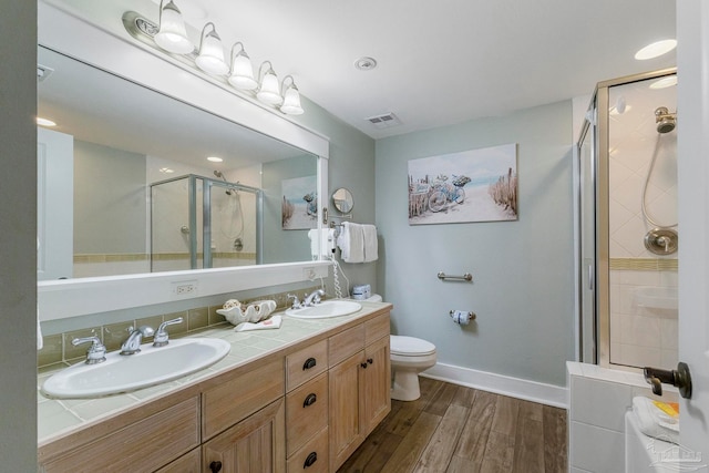 bathroom featuring a shower with door, vanity, wood-type flooring, and toilet