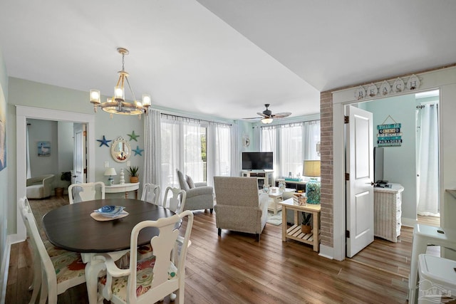 dining space with hardwood / wood-style floors and ceiling fan with notable chandelier