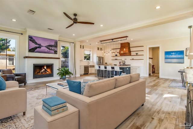 living room with plenty of natural light, ceiling fan, ornamental molding, and light hardwood / wood-style flooring