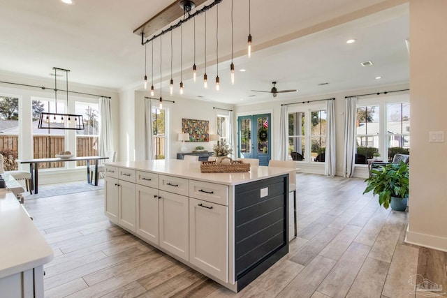 kitchen featuring a center island, white cabinets, ceiling fan, decorative light fixtures, and light hardwood / wood-style floors