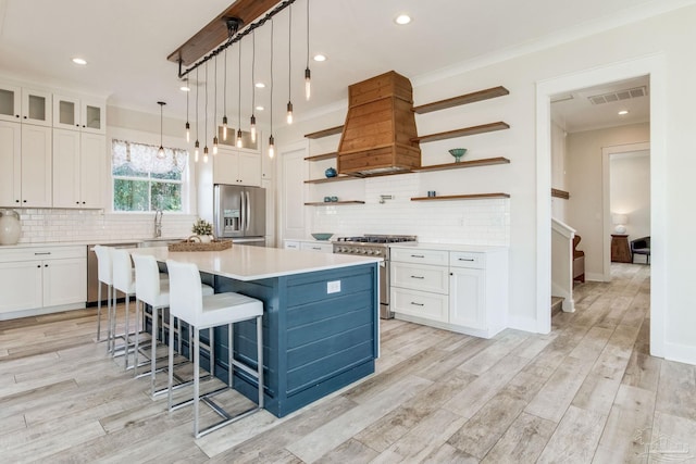 kitchen featuring white cabinets, a center island, stainless steel appliances, and hanging light fixtures