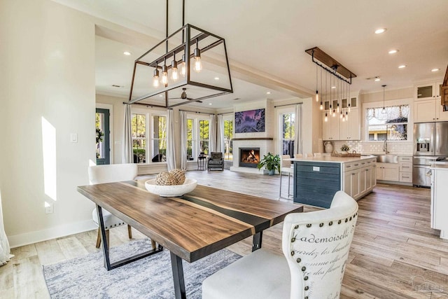 dining space with ceiling fan, light wood-type flooring, sink, and a wealth of natural light