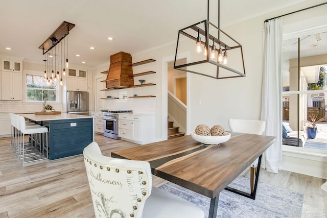 dining area featuring light wood-type flooring and crown molding