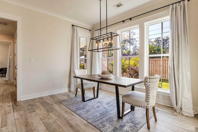 dining area with light hardwood / wood-style floors, ornamental molding, and a notable chandelier