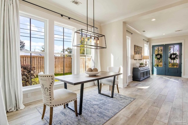 dining room featuring french doors, light hardwood / wood-style floors, and crown molding