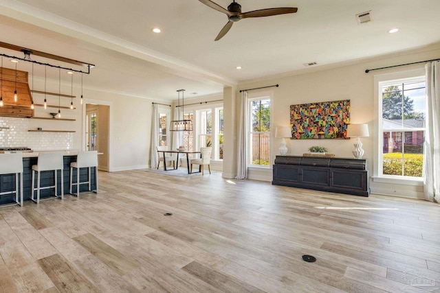 unfurnished living room featuring plenty of natural light, light hardwood / wood-style floors, and ornamental molding