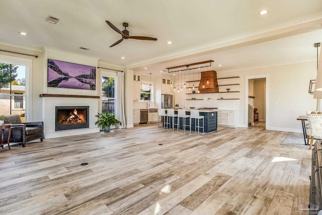 living room featuring crown molding, light hardwood / wood-style flooring, and a healthy amount of sunlight