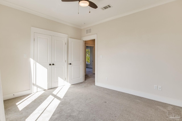 carpeted empty room featuring ceiling fan and crown molding