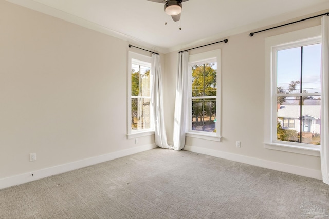 carpeted spare room with ceiling fan, ornamental molding, and a wealth of natural light