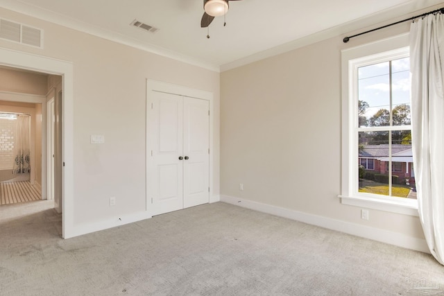 unfurnished bedroom featuring ceiling fan, ornamental molding, light carpet, and a closet