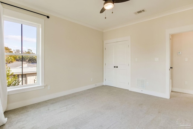 unfurnished bedroom with multiple windows, light carpet, and ceiling fan