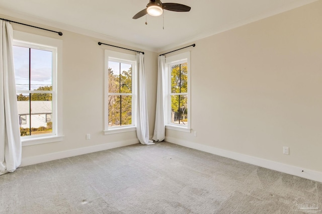 empty room with ceiling fan, a healthy amount of sunlight, light colored carpet, and crown molding