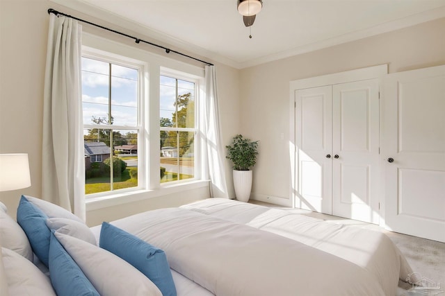 bedroom with ceiling fan, ornamental molding, light carpet, and a closet