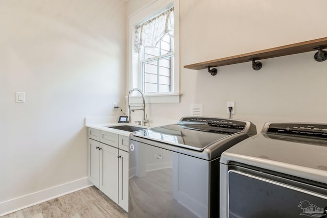 washroom featuring washer and clothes dryer, a healthy amount of sunlight, cabinets, and sink