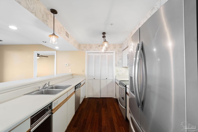 kitchen with appliances with stainless steel finishes, decorative light fixtures, sink, white cabinetry, and dark hardwood / wood-style floors