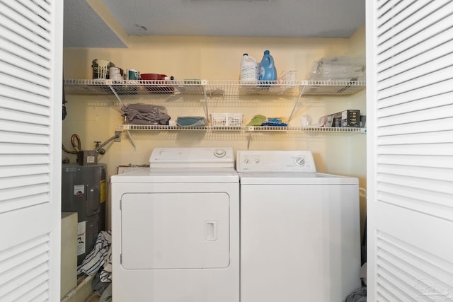 clothes washing area featuring electric water heater and washer and clothes dryer