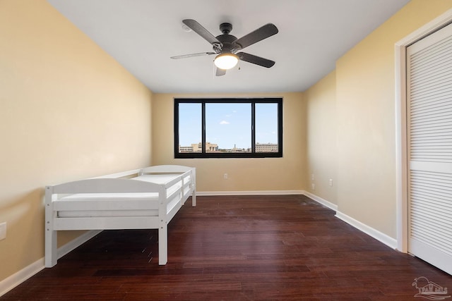 unfurnished bedroom with a closet, dark hardwood / wood-style floors, and ceiling fan