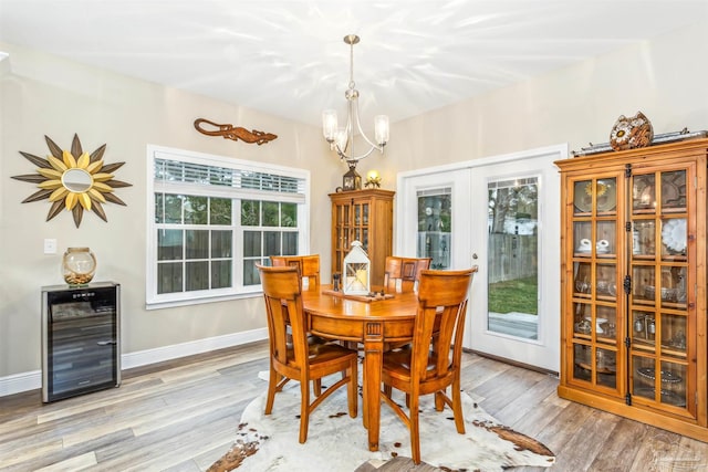 dining space featuring a chandelier, french doors, light hardwood / wood-style flooring, and wine cooler