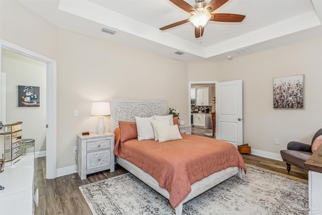 bedroom featuring ceiling fan, a raised ceiling, and dark wood-type flooring