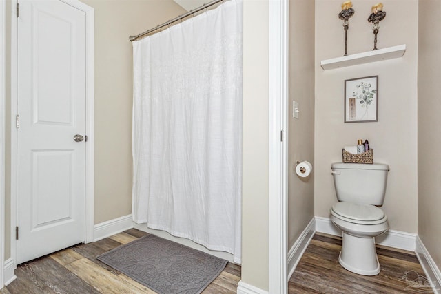 bathroom featuring wood-type flooring, toilet, and a shower with curtain