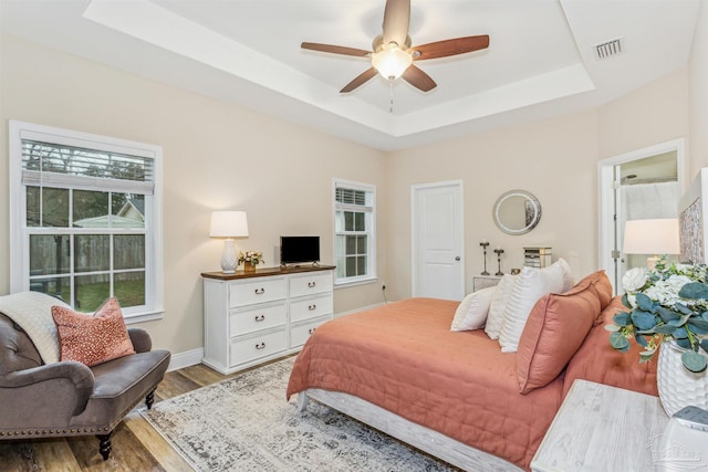 bedroom featuring a tray ceiling, ceiling fan, and light wood-type flooring