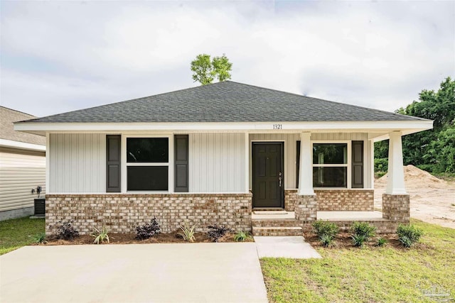 view of front of house featuring covered porch, brick siding, and a shingled roof