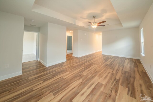 spare room featuring light hardwood / wood-style floors, a raised ceiling, and ceiling fan