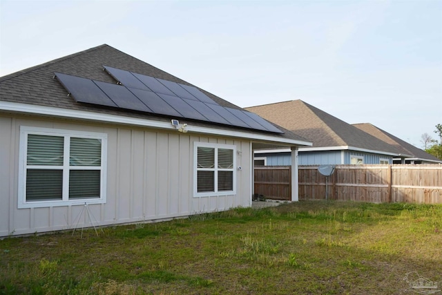 back of property featuring a lawn and solar panels