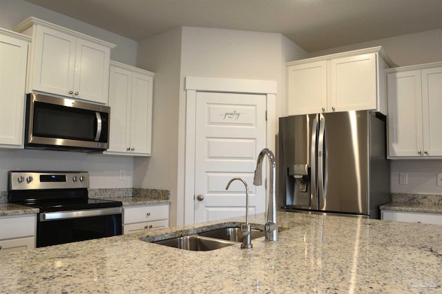 kitchen with sink, appliances with stainless steel finishes, light stone counters, and white cabinets