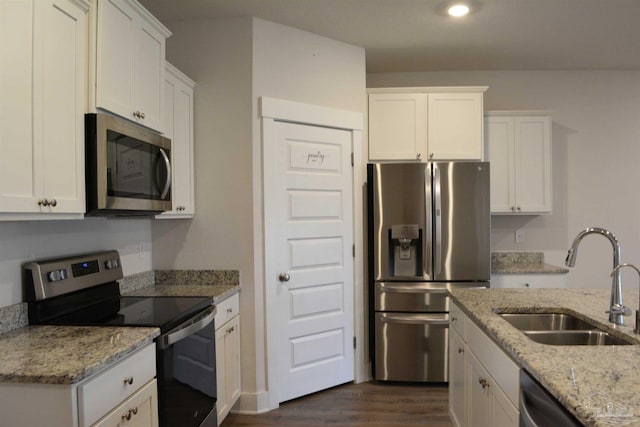 kitchen featuring appliances with stainless steel finishes, sink, light stone counters, white cabinetry, and dark hardwood / wood-style flooring