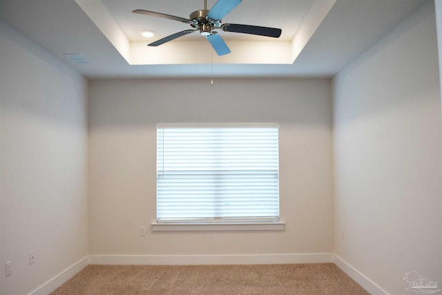 carpeted empty room with a tray ceiling and ceiling fan
