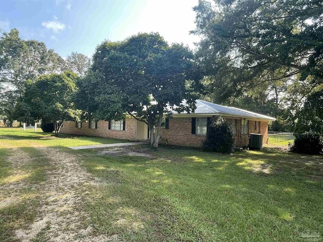 view of side of home with a lawn, driveway, fence, brick siding, and central AC unit