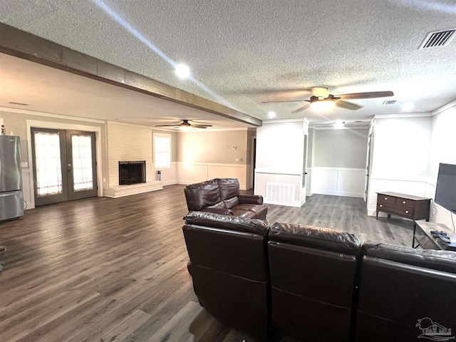 living room with visible vents, dark wood-type flooring, a fireplace, and wainscoting