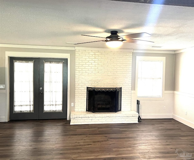 unfurnished living room featuring a wainscoted wall, a brick fireplace, wood finished floors, and french doors