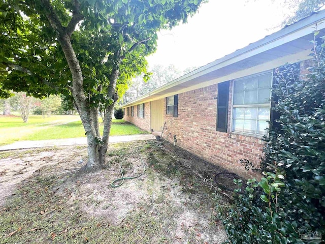 view of side of home featuring a lawn and brick siding