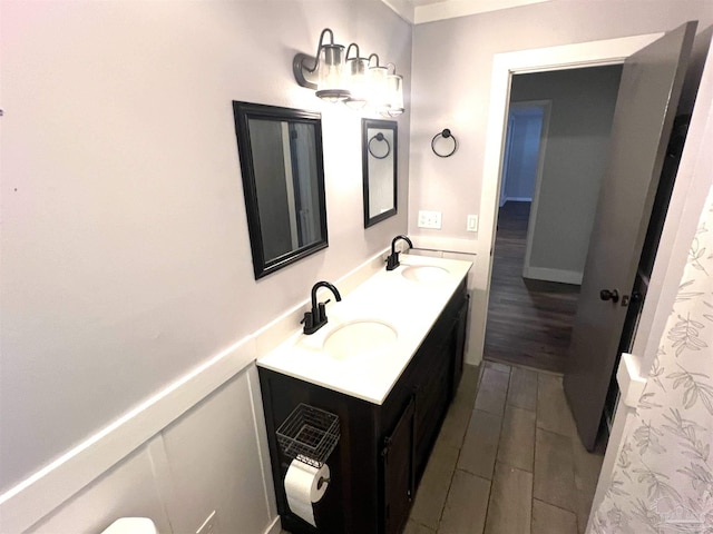 bathroom with double vanity, wood finished floors, wainscoting, and a sink