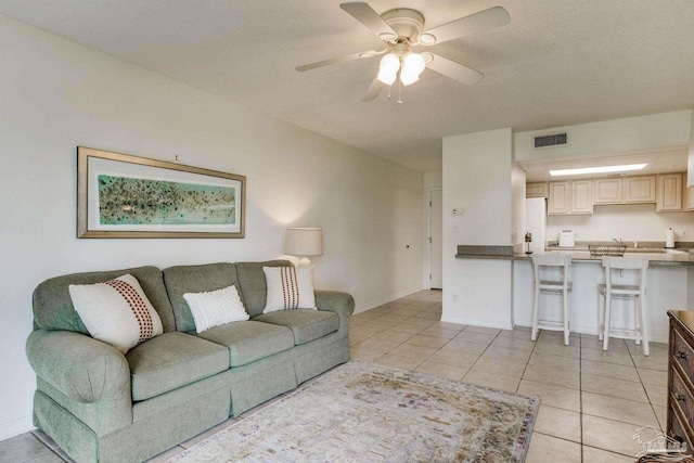 living room featuring a textured ceiling, light tile patterned floors, and ceiling fan