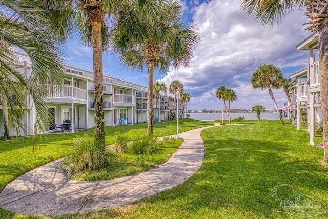 view of property's community with a water view and a lawn