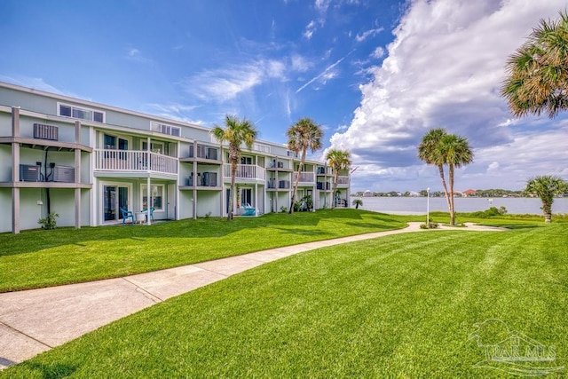 surrounding community with a water view and a lawn