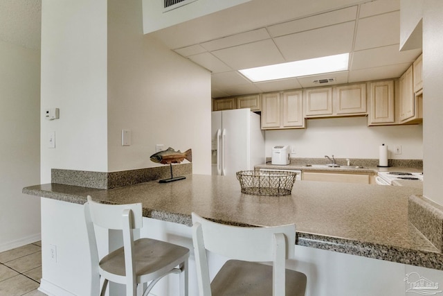 kitchen with sink, kitchen peninsula, a kitchen bar, and white appliances