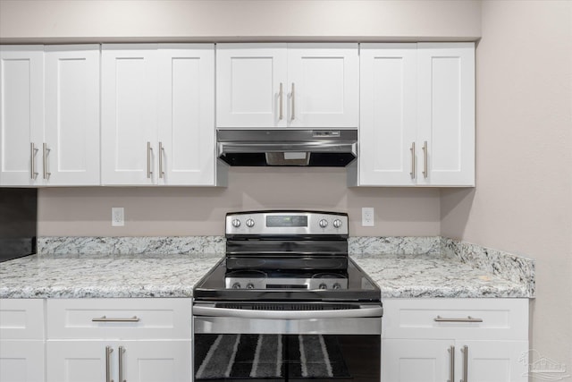 kitchen with light stone countertops, white cabinets, and electric stove