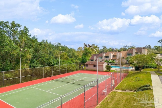 view of tennis court with a fenced in pool and a lawn