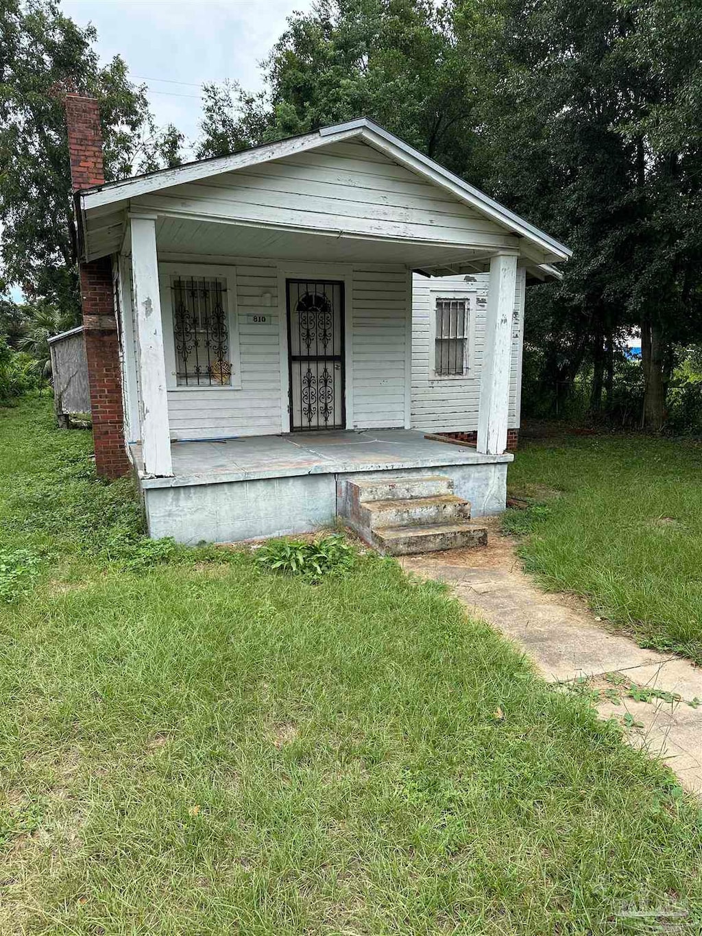 bungalow-style home featuring covered porch and a front lawn