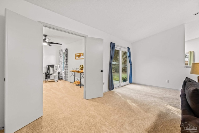 living room featuring light carpet, a textured ceiling, and ceiling fan