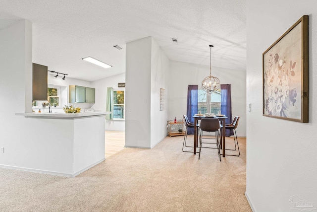 dining space featuring light carpet, a chandelier, and a textured ceiling