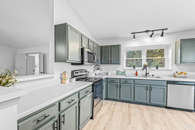 kitchen featuring sink, light wood-type flooring, stainless steel appliances, and vaulted ceiling