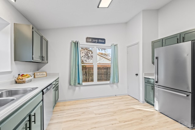 kitchen featuring light hardwood / wood-style flooring, green cabinets, stainless steel appliances, and vaulted ceiling