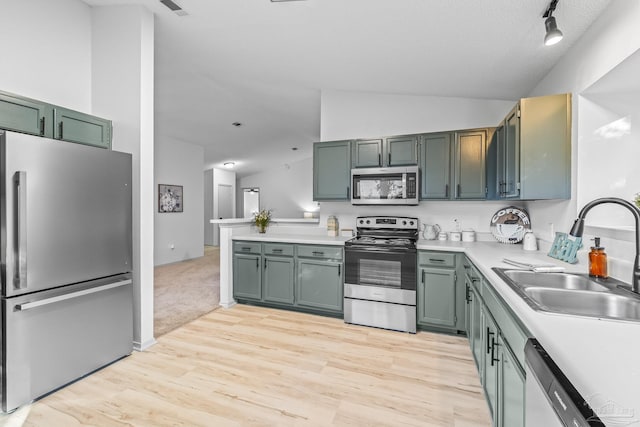 kitchen featuring green cabinets, sink, lofted ceiling, and appliances with stainless steel finishes