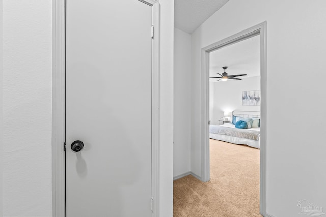 corridor with light carpet and a textured ceiling