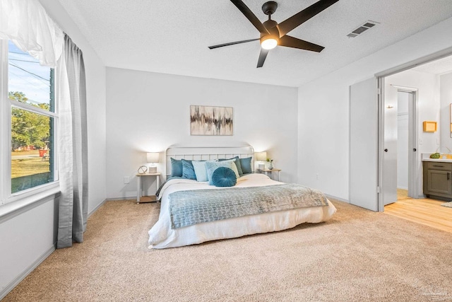 carpeted bedroom featuring a textured ceiling, ceiling fan, and ensuite bathroom